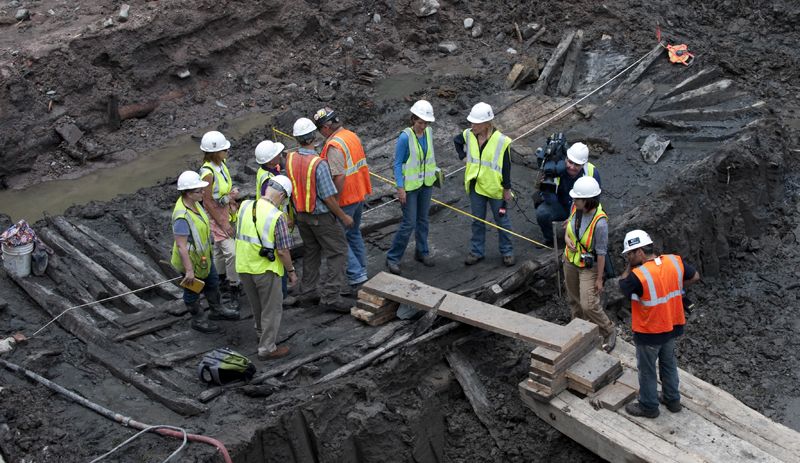 Workers and members of the media inspect the hull of a late 18th or early 19th century ship found at the World Trade Center site